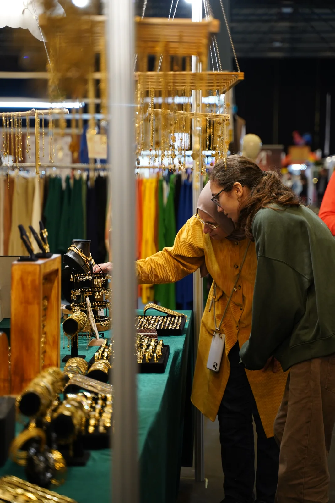 Besucherinnen entdecken Schmuck an einem Ausstellerstand